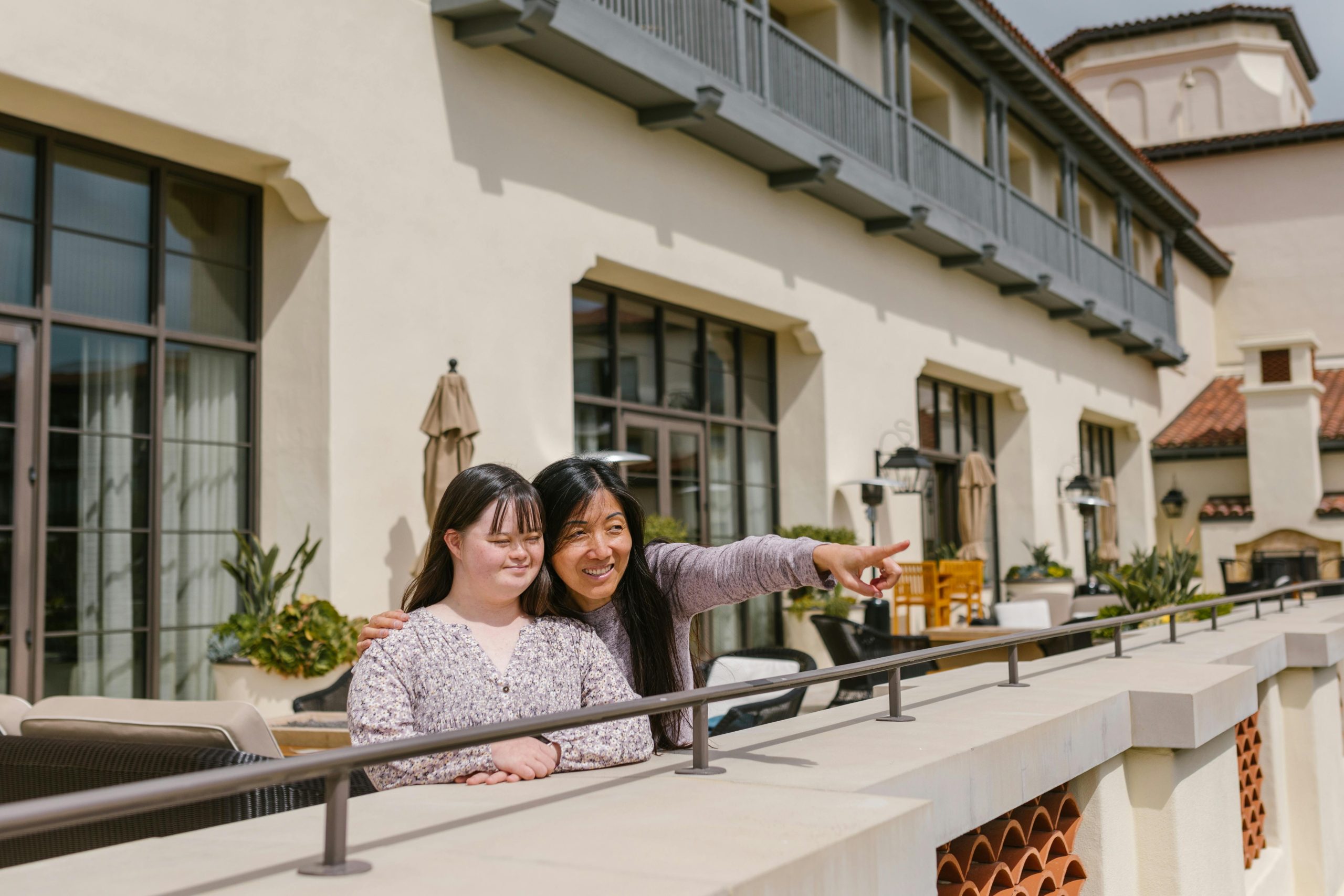 Mother and daughter share a special bonding moment on a sunny balcony.