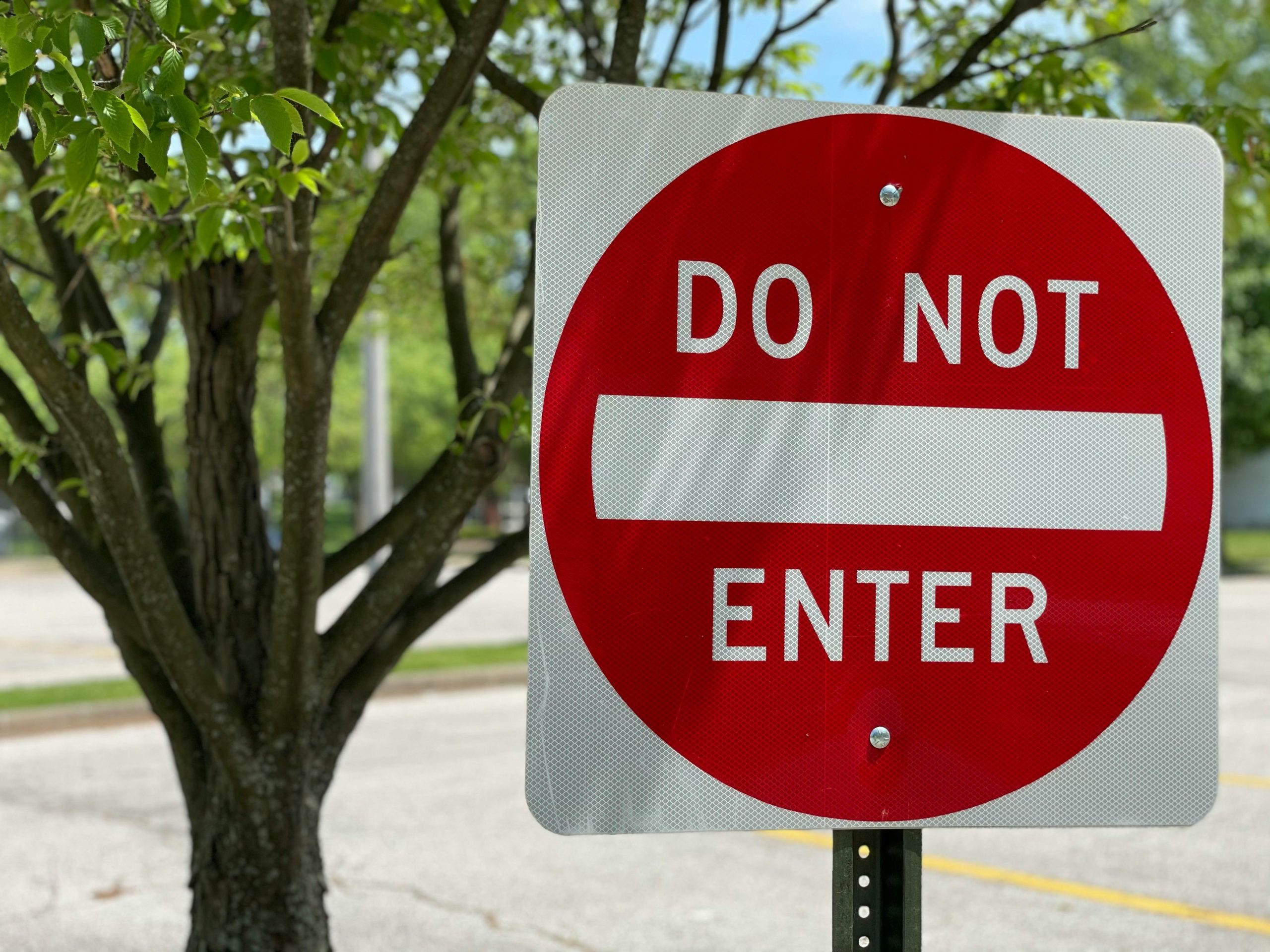 Close-up of a red do not enter sign in a leafy outdoor environment indicating no entry.